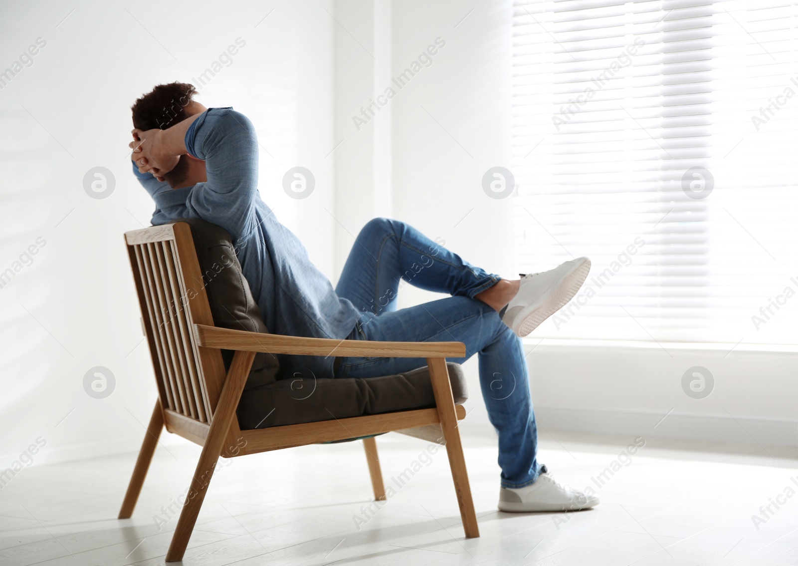 Photo of Young man relaxing in armchair near window at home