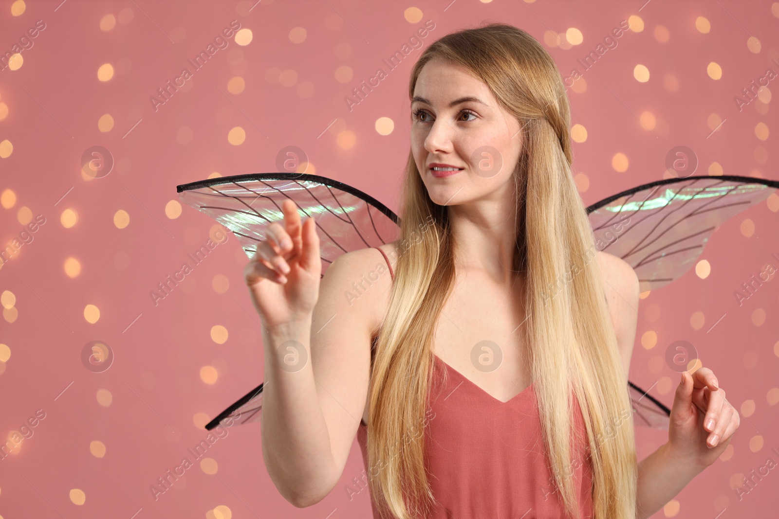 Photo of Beautiful girl in fairy costume with wings on pink background