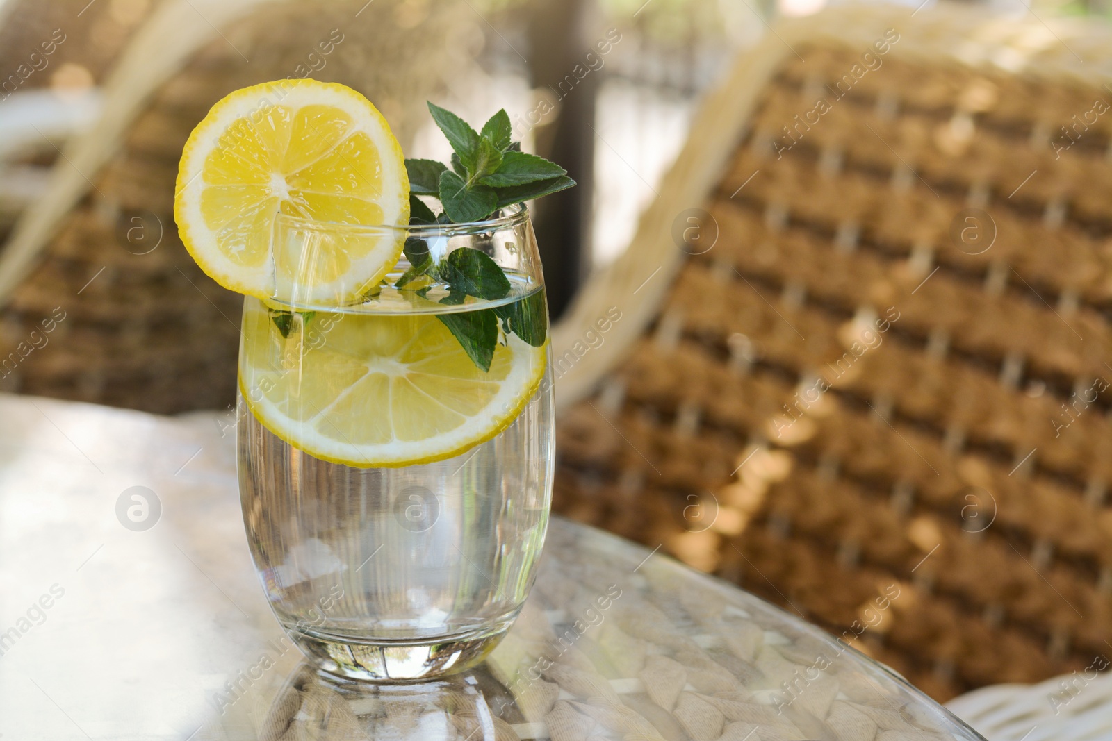 Photo of Refreshing water with lemon and mint on glass table in cafe, space for text