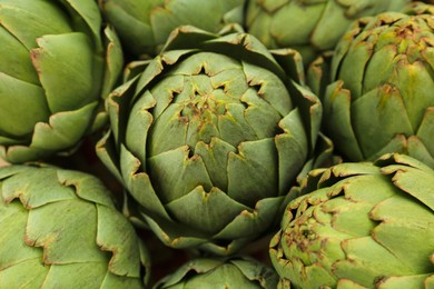 Photo of Many fresh raw artichokes as background, top view