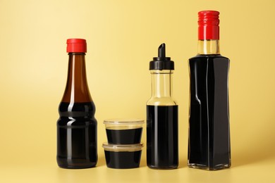 Photo of Bottles with soy sauce on yellow background