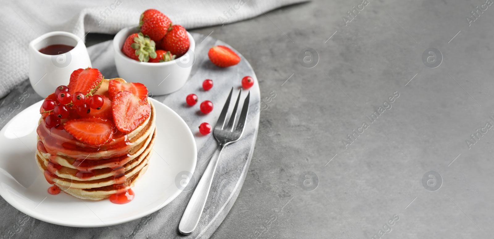 Image of Tasty pancakes with berries served on grey table, space for text. Banner design