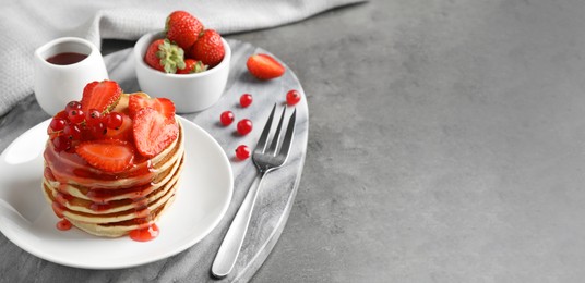 Tasty pancakes with berries served on grey table, space for text. Banner design