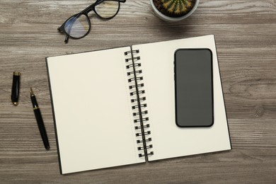 Photo of Flat lay composition with notebook and smartphone on wooden table