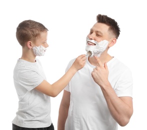 Son applying shaving foam on dad's face, white background