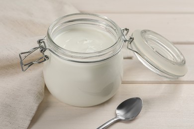 Photo of Jar of tasty organic yogurt on white wooden table