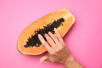 Photo of Young woman touching half of papaya on pink background, top view. Sex concept