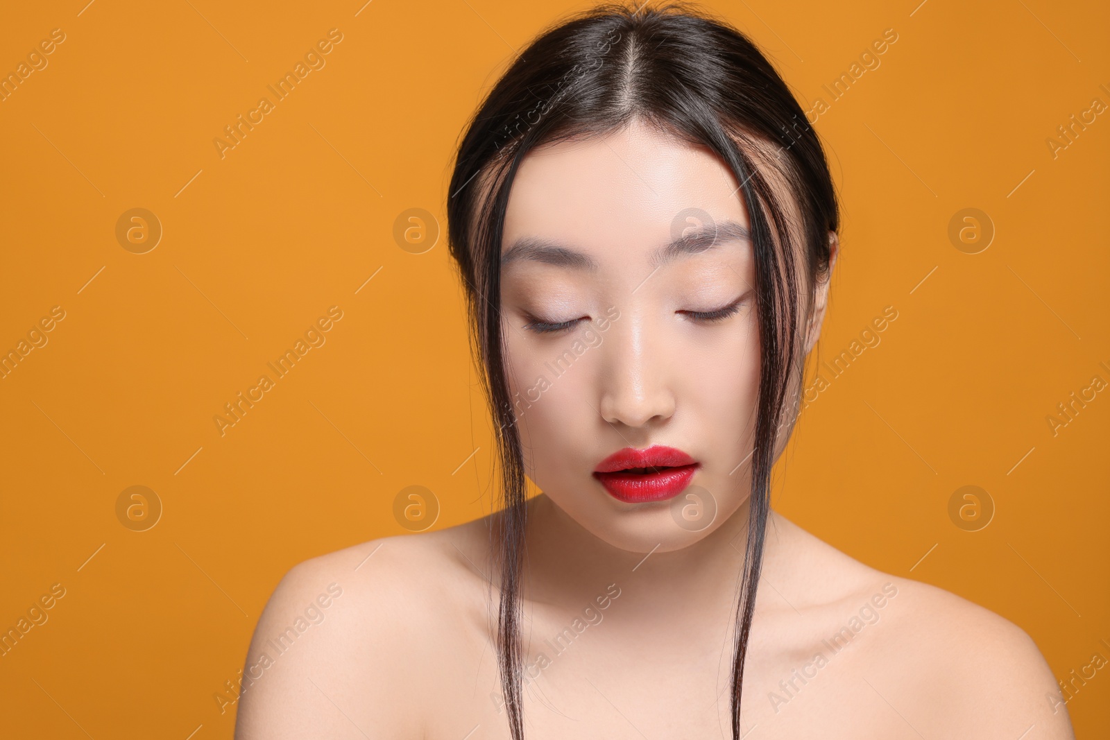 Photo of Portrait of beautiful young Asian woman on orange background, space for text