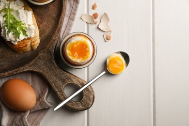 Breakfast with soft boiled egg served on white wooden table, flat lay. Space for text