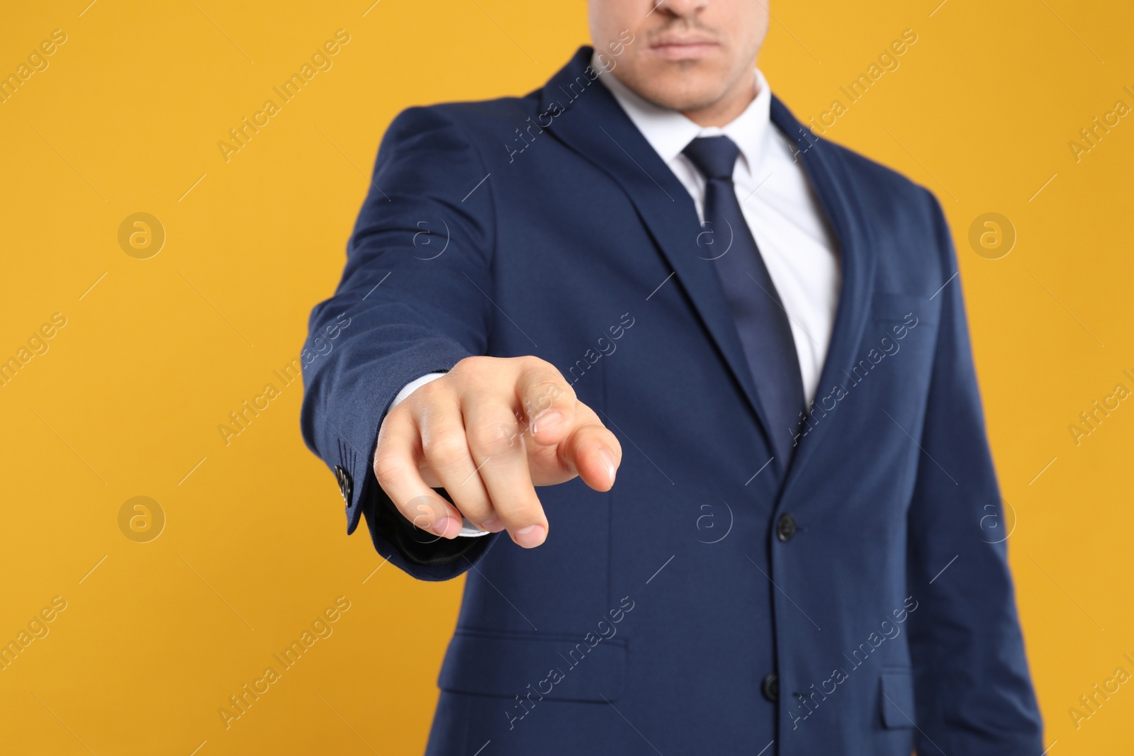 Photo of Businessman touching something on yellow background, closeup. Finger gesture