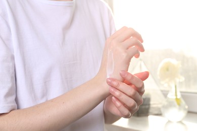 Photo of Woman applying hand cream at home, closeup