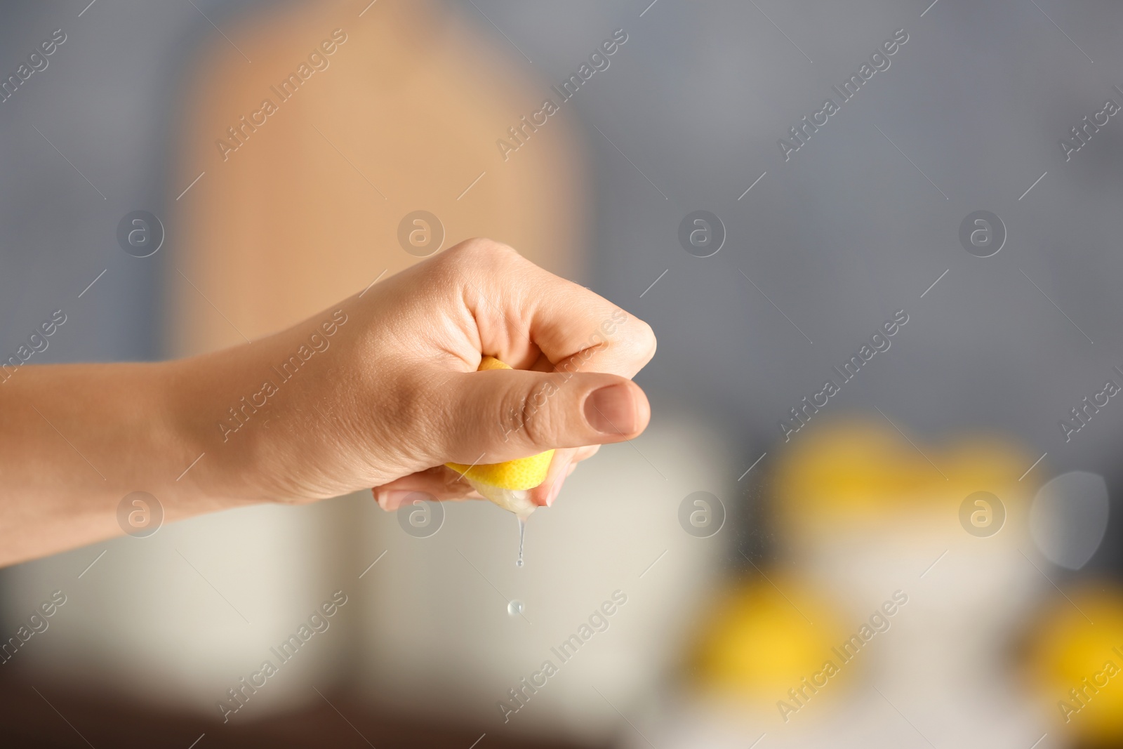 Photo of Young woman squeezing lemon on blurred background