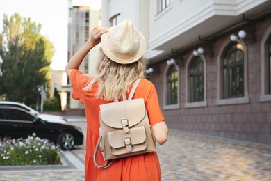 Photo of Young woman with stylish backpack outdoors, back view