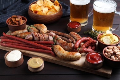 Set of different tasty snacks and beer on wooden table