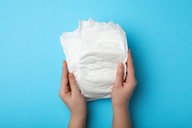 Photo of Woman with diapers on light blue background, closeup