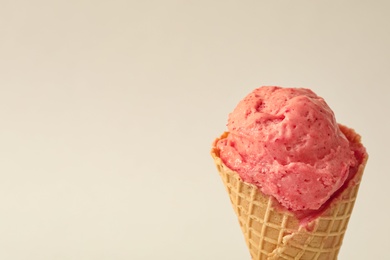 Photo of Delicious pink ice cream in waffle cone on white background, closeup. Space for text