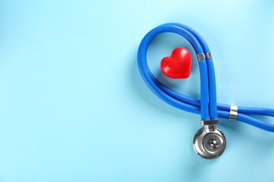 Photo of Stethoscope and small red heart on color background. Heart attack concept