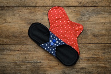 Reusable cloth menstrual pads on wooden table, flat lay