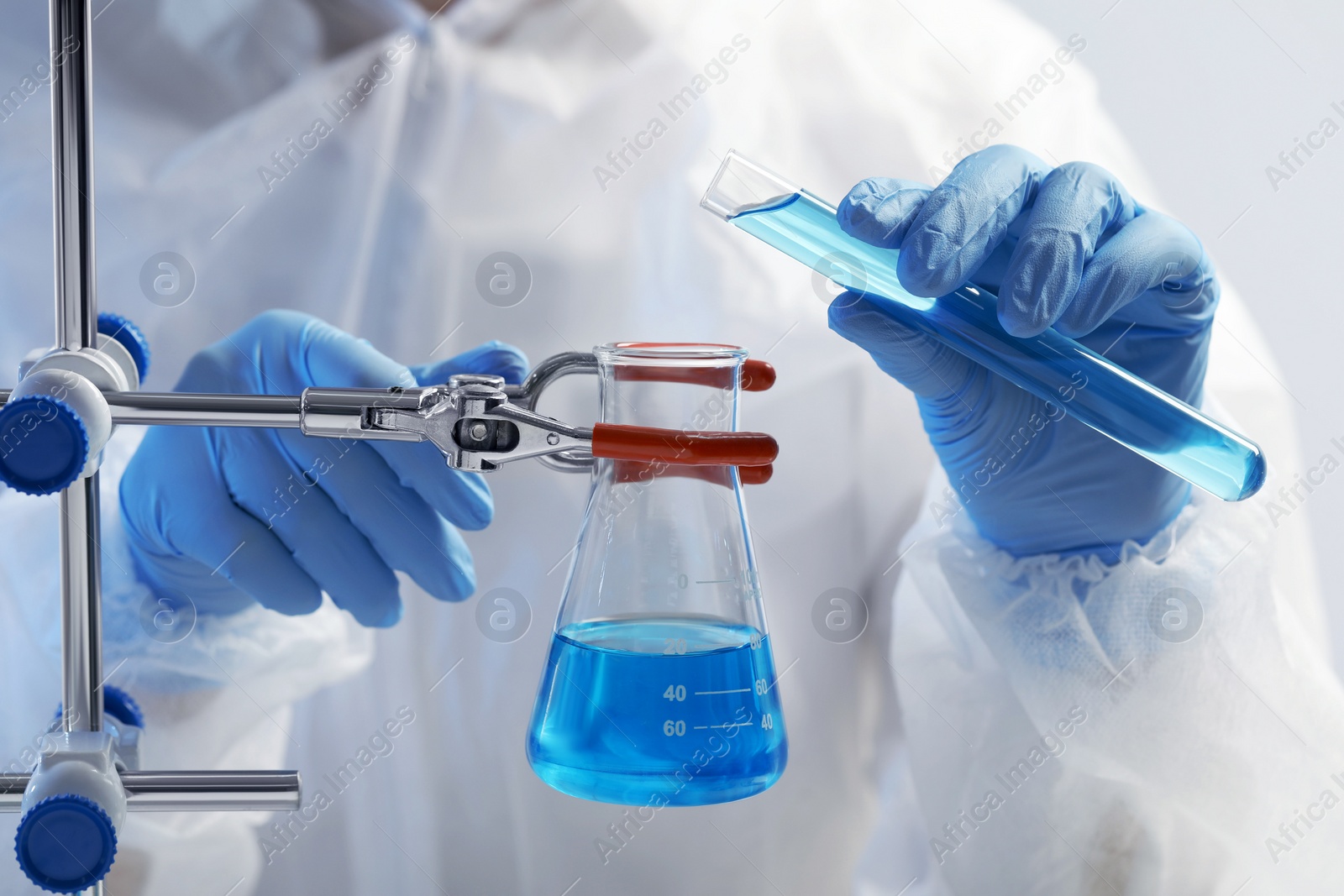 Photo of Scientist working with beaker and test tube on grey background, closeup