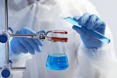 Scientist working with beaker and test tube on grey background, closeup