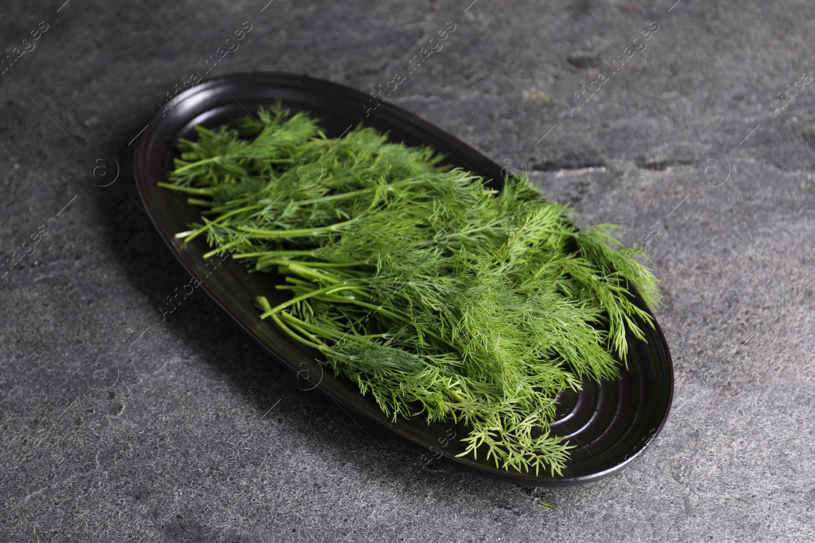 Photo of Sprigs of fresh green dill on grey table