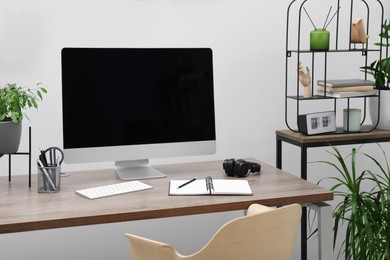 Photo of Cozy workspace with computer on desk near white wall at home