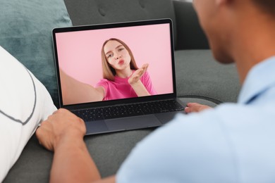 Long distance love. Man having video chat with his girlfriend via laptop at home, closeup