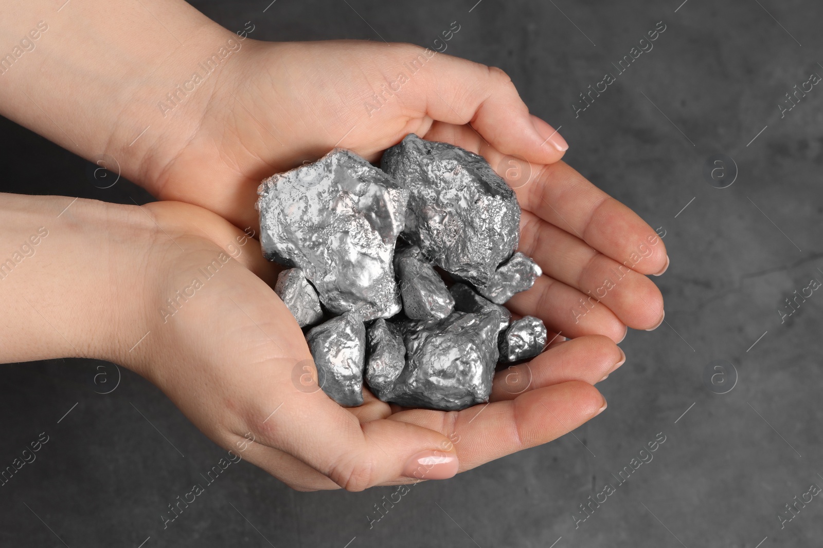 Photo of Woman with silver nuggets at grey table, closeup