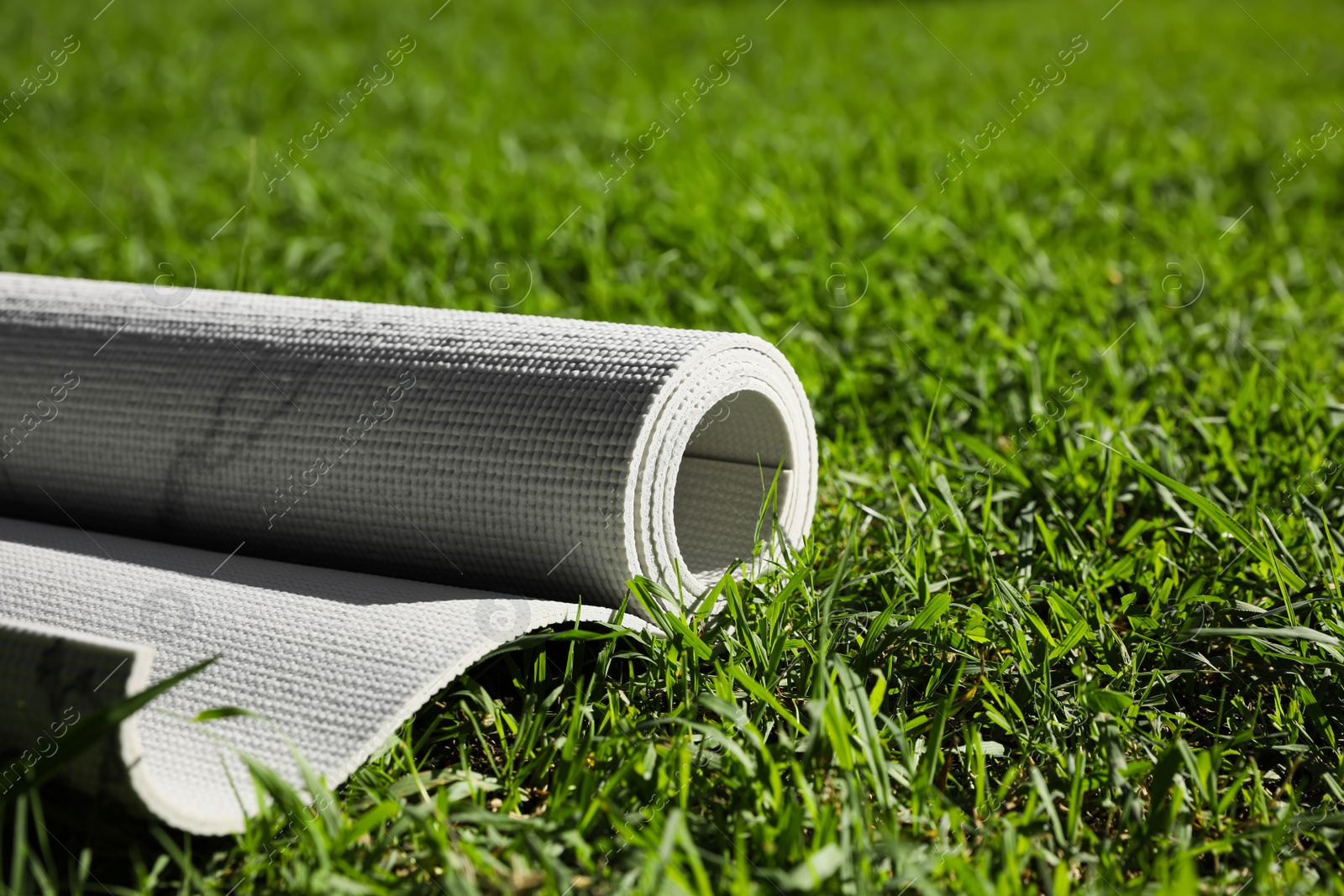 Photo of Karemat or fitness mat on green grass outdoors, closeup. Space for text