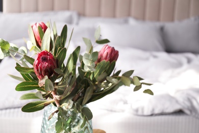 Photo of Vase with bouquet of beautiful Protea flowers in bedroom, closeup