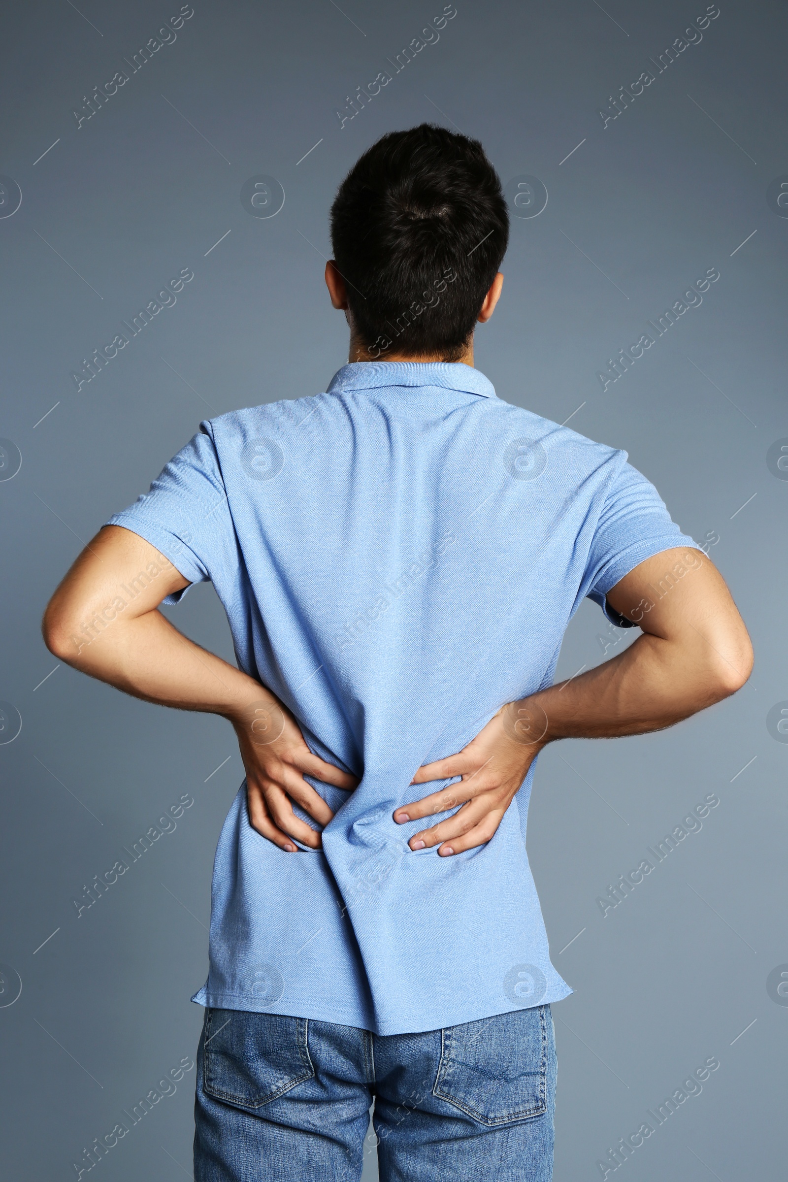 Photo of Man suffering from back pain on grey background