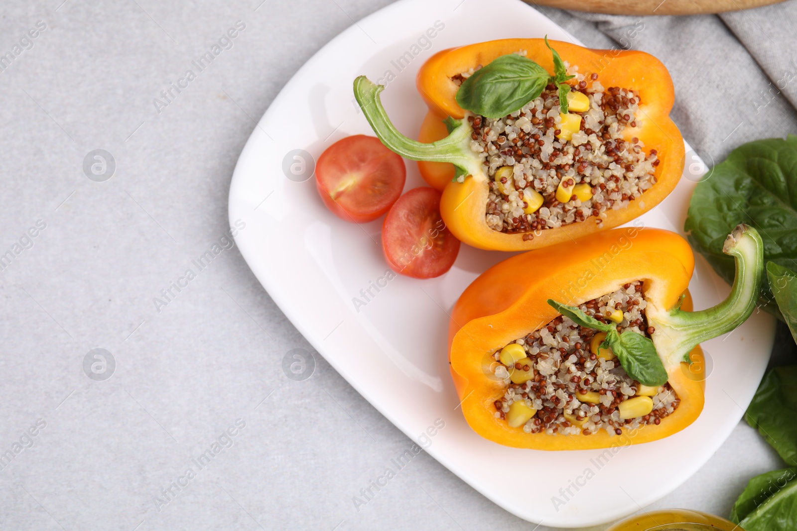 Photo of Quinoa stuffed bell pepper with basil and tomato on light table, top view. Space for text