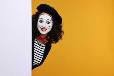 Photo of Funny mine with blank poster posing on orange background, space for text