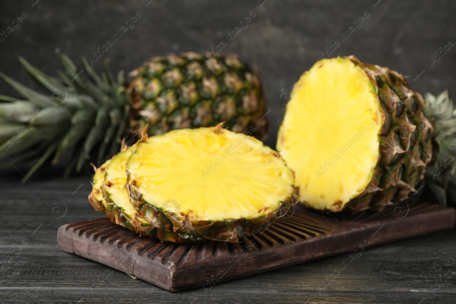 Photo of Board with cut fresh juicy pineapple on wooden table, closeup