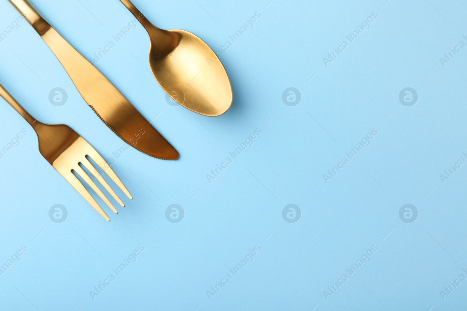 Photo of Stylish cutlery set on light blue table, flat lay. Space for text