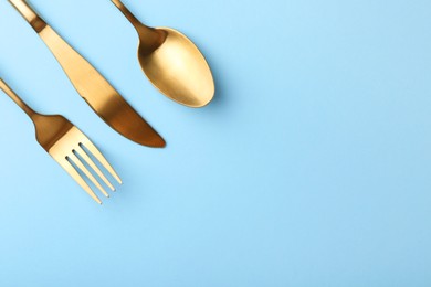 Photo of Stylish cutlery set on light blue table, flat lay. Space for text