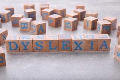 Photo of Wooden cubes with word Dyslexia on light grey stone table