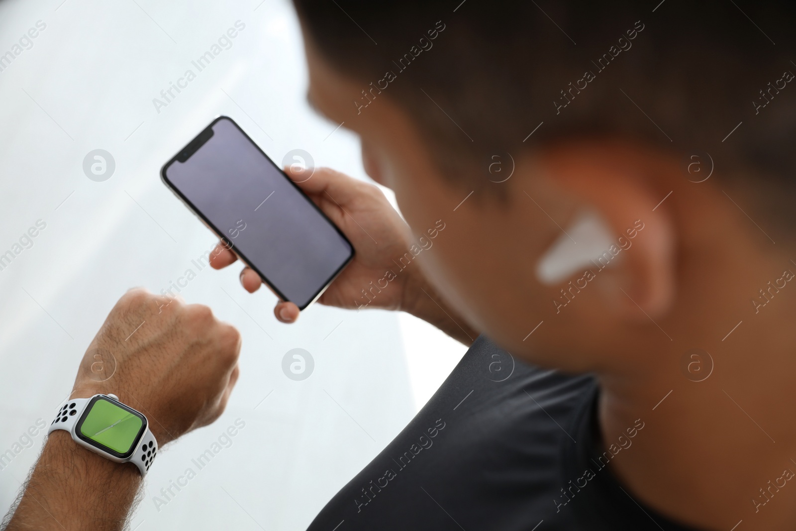 Photo of Man with smartphone checking fitness tracker in gym, closeup