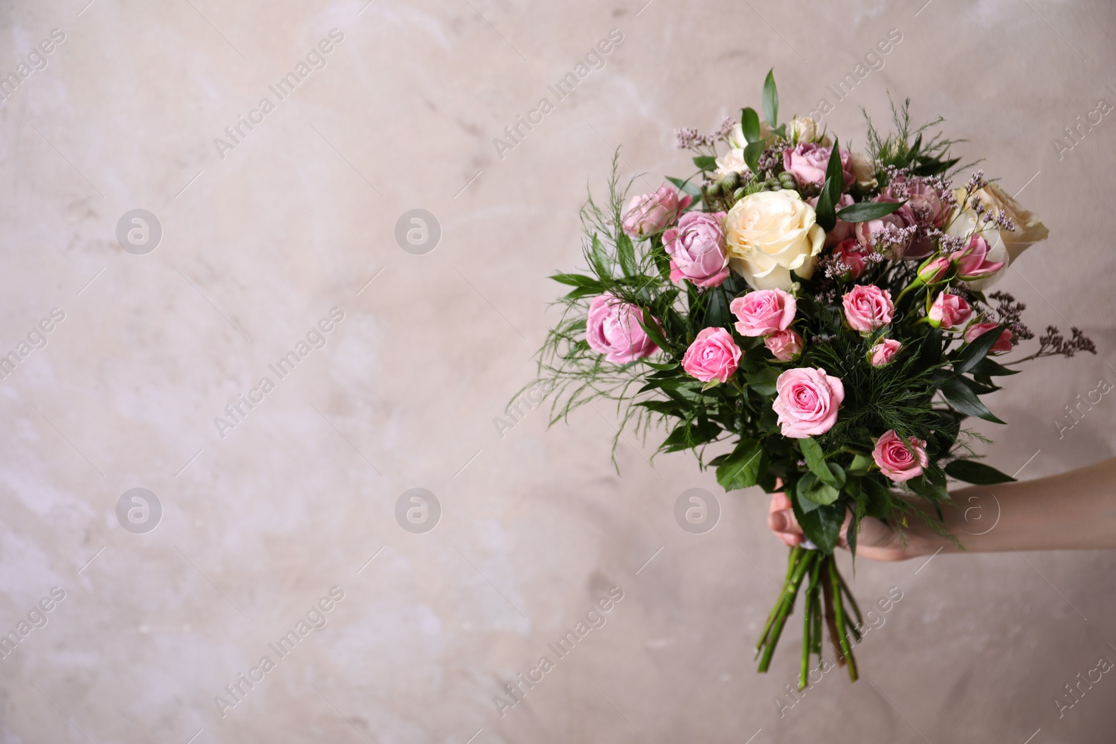 Photo of Woman with bouquet of beautiful roses on beige background, closeup. Space for text