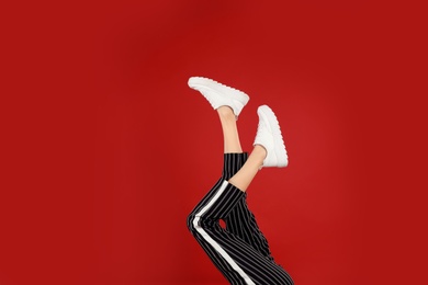 Photo of Woman in stylish sport shoes on red background