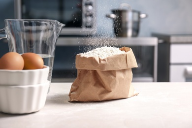 Sifting flour into paper package on table in kitchen