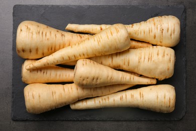 Delicious fresh ripe parsnips on black table, top view