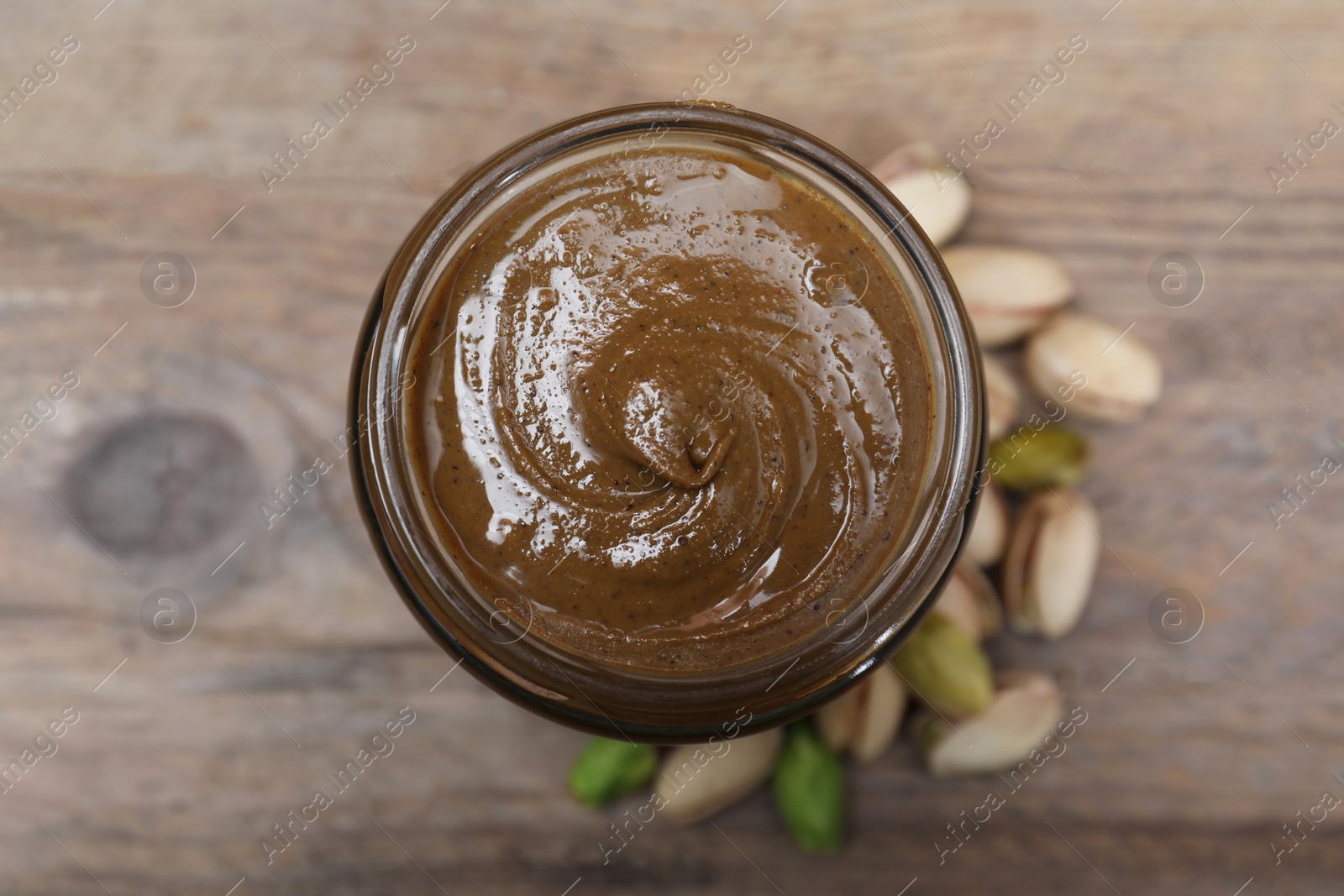 Photo of Tasty pistachio nut paste in jar on table, top view