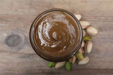 Photo of Tasty pistachio nut paste in jar on table, top view