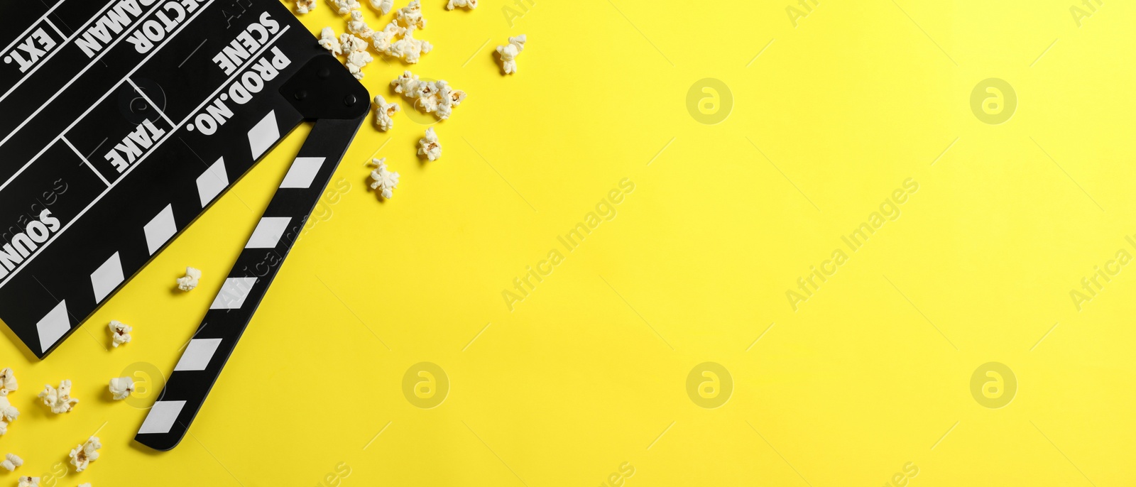 Image of Clapper board and popcorn on yellow background, flat lay with space for text. Banner design