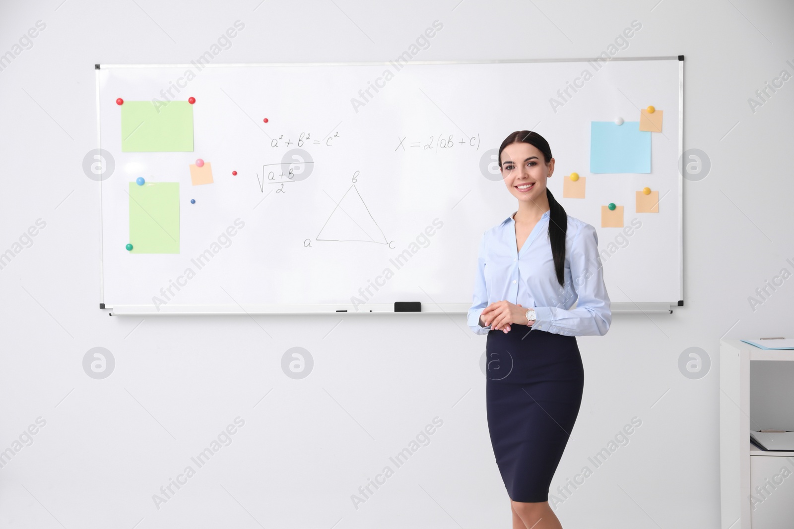 Photo of Young teacher near whiteboard in modern classroom. Space for text