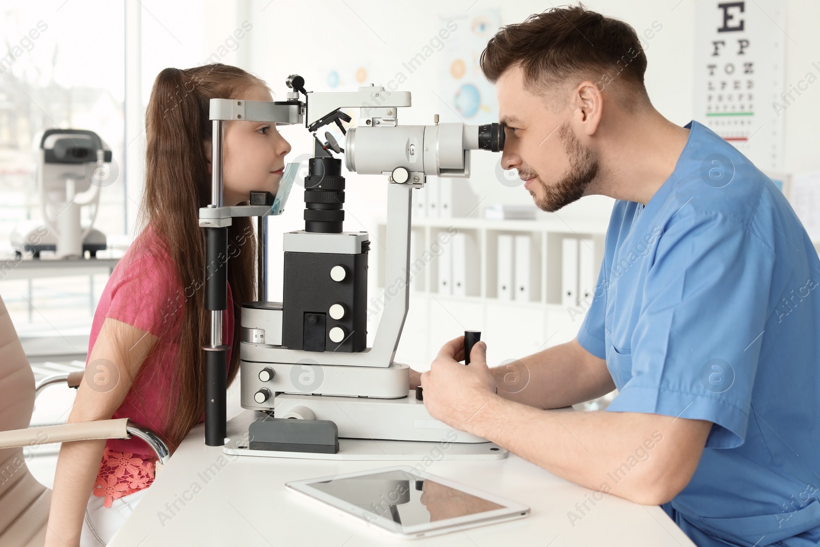 Photo of Ophthalmologist examining little girl in clinic