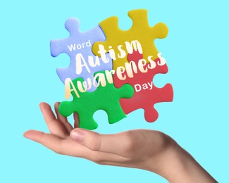 Image of World Autism Awareness Day. Woman holding colorful puzzle pieces on light blue background, closeup