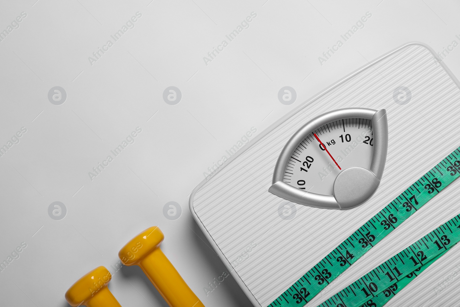 Photo of Weight loss concept. Scales, dumbbells and measuring tape on white background, flat lay. Space for text