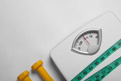 Photo of Weight loss concept. Scales, dumbbells and measuring tape on white background, flat lay. Space for text